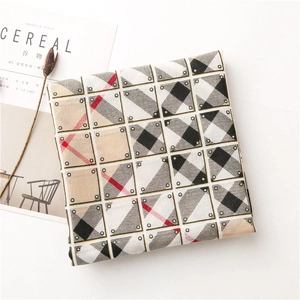 Detail of a beige checkered scarf with fine diagonal texture on a minimalist background