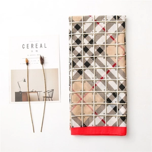 Detail of checkered summer scarf with fringe and red border on white background