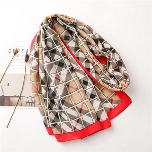 Detail of a geometric lattice scarf with red edges laid over a minimalist magazine