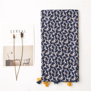 Detail of cotton linen scarf with blue and orange floral pattern and colorful tassels