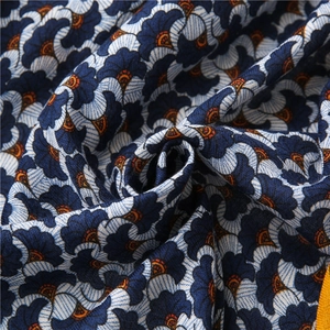 Detailed macro view of retro floral print cotton-linen fabric with blue petals and orange accents