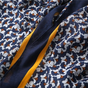 Detailed view of floral blue scarf fabric with orange accents and fine stitching