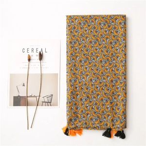 Detail of cotton linen scarf with vintage yellow fan patterns and orange fringe tassels