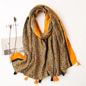 Artistic orange cotton-linen scarf with floral prints and tassels on white background