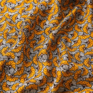 Macro detail of scarf fabric showing yellow floral patterns and fine woven texture