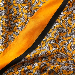 Detailed macro view of yellow floral pattern cotton linen scarf with orange border