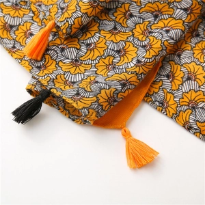 Detail of cotton linen scarf showing yellow floral patterns and fringe tassels