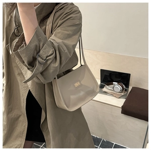Detail of a beige faux leather underarm bag with a golden plate and slim shoulder strap