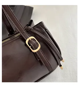 Dettaglio borsa a spalla in pelle marrone scuro con fibbia dorata e tracolla regolabile