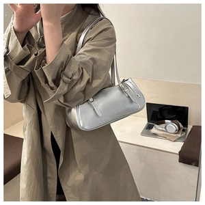 Dettaglio della borsa a spalla argento metallizzato indossata su un trench color kaki