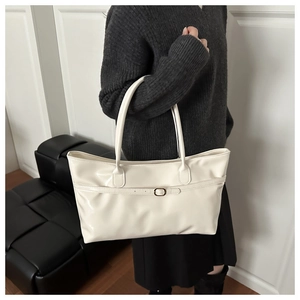 Détail d'un cabas en cuir verni crème avec boucle métallique et finition brillante