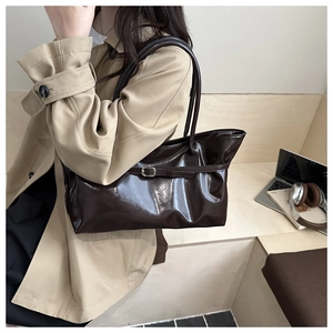 Détail d'un sac cabas en cuir verni brillant marron foncé avec boucle décorative élégante