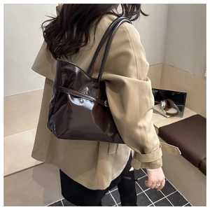 Sac cabas en cuir verni marron foncé avec fines bandoulières porté par un mannequin