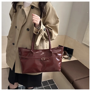 Détail d'un grand sac cabas bordeaux en similicuir porté par un mannequin au bureau