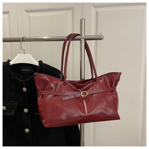 Vue détaillée du sac cabas bordeaux brillant avec sangles et boucles métalliques
