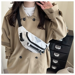 Close-up of beige crossbody bag with grey triangle logo worn over a trench coat