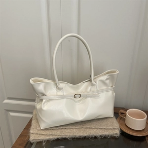 Sac cabas en similicuir blanc crème avec boucle décorative sur une table en bois