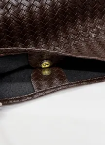 Dettaglio della borsa in pelle marrone intrecciata con chiusura magnetica dorata