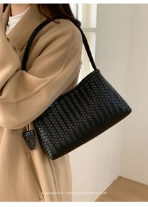 Détail du sac bandoulière en cuir tressé noir avec un style rétro et minimaliste