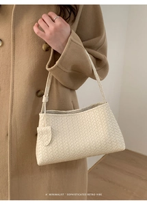 Détail du sac baguette tissé crème avec texture complexe et style rétro minimaliste