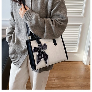 Détail du sac cabas contrasté avec texture peau de serpent et foulard en soie