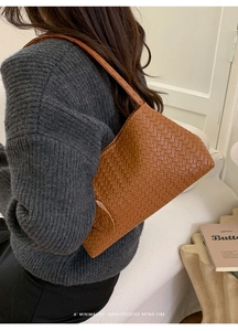 Vue détaillée du sac bandoulière en cuir tressé marron caramel porté par un modèle