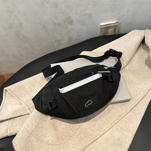 Black waterproof nylon crossbody bag with reflective stripe on beige coat background