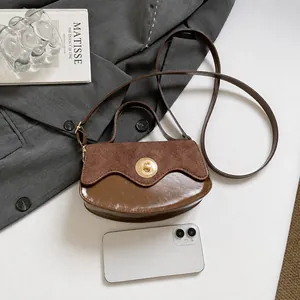 Dettaglio della borsa a tracolla patchwork marrone con chiusura dorata e smartphone di scala