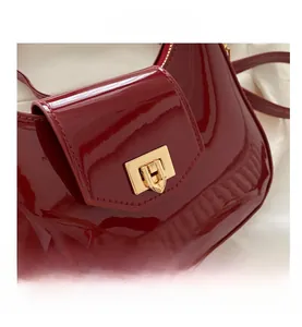 Close-up of glossy burgundy patent leather handbag with elegant gold metal buckle