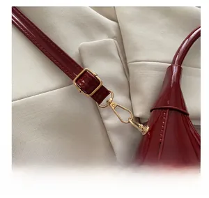 Detail of dark red patent leather dumpling bag with polished gold hardware hooks