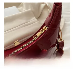 Detail of glossy red patent leather bag showing smooth gold metal zipper and hardware