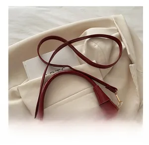Detail of red patent leather dumpling bag with glossy finish on a cream blazer
