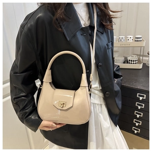 Detail of beige patent leather dumpling bag with gold buckle and stylish top handle