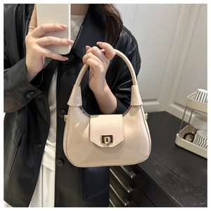 Close-up of beige glossy patent leather handbag with stylish metal buckle detail