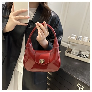 Mirror selfie showing a glossy red patent leather hobo bag with gold shield lock detail