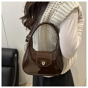 Detail of glossy brown patent leather hobo bag with an elegant golden square metal lock