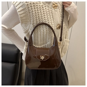 Close-up of brown patent leather handbag featuring glossy finish and gold metal buckle