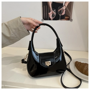 Detail of black patent leather dumpling bag with gold metal buckle and glossy finish