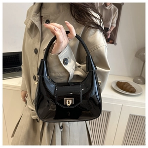 Detail of black patent leather handbag with gold metal clasp and sleek bell-shaped hardware