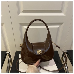 Detail view of dark brown patent leather dumpling bag with elegant gold square metal buckle