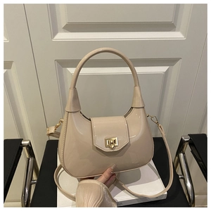Detail of beige glossy patent leather crescent bag with gold twist lock and handle