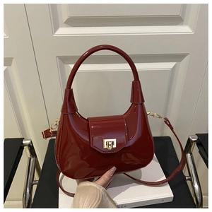 Detail of red patent leather dumpling bag featuring a golden rectangular metal lock
