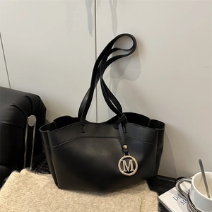 Chic black matte tote bag with golden M pendant, styled with a scarf and coffee cup