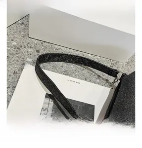 Détail de sac à bandoulière noir pailleté montrant la sangle et les anneaux métalliques