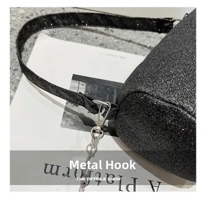 Détail du crochet en métal argenté et chaîne sur un sac à bandoulière noir brillant