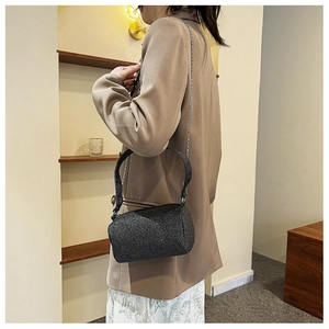 Détail du sac cylindre à paillettes noires avec chaîne argentée et texture scintillante