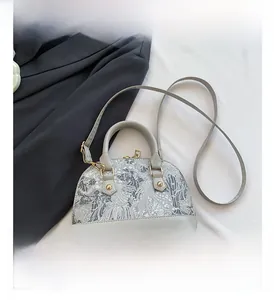 Détail du sac bandoulière en forme de coquillage avec broderie florale grise complexe