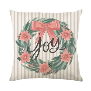 Pink Christmas pillow cover with festive wreath and hand-lettered joy text on beige fabric