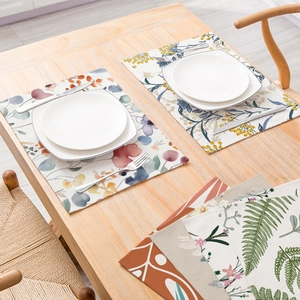 Linen placemat with floral and fern patterns on a warm wooden dining table
