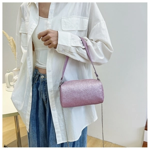 Gros plan du sac tonneau rose pailleté avec bandoulière chaîne et poignée en cuir